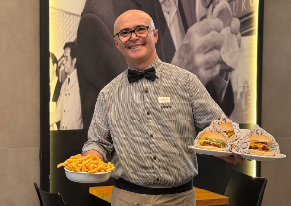Garçom da Osnir servindo hambúrgueres e batatas